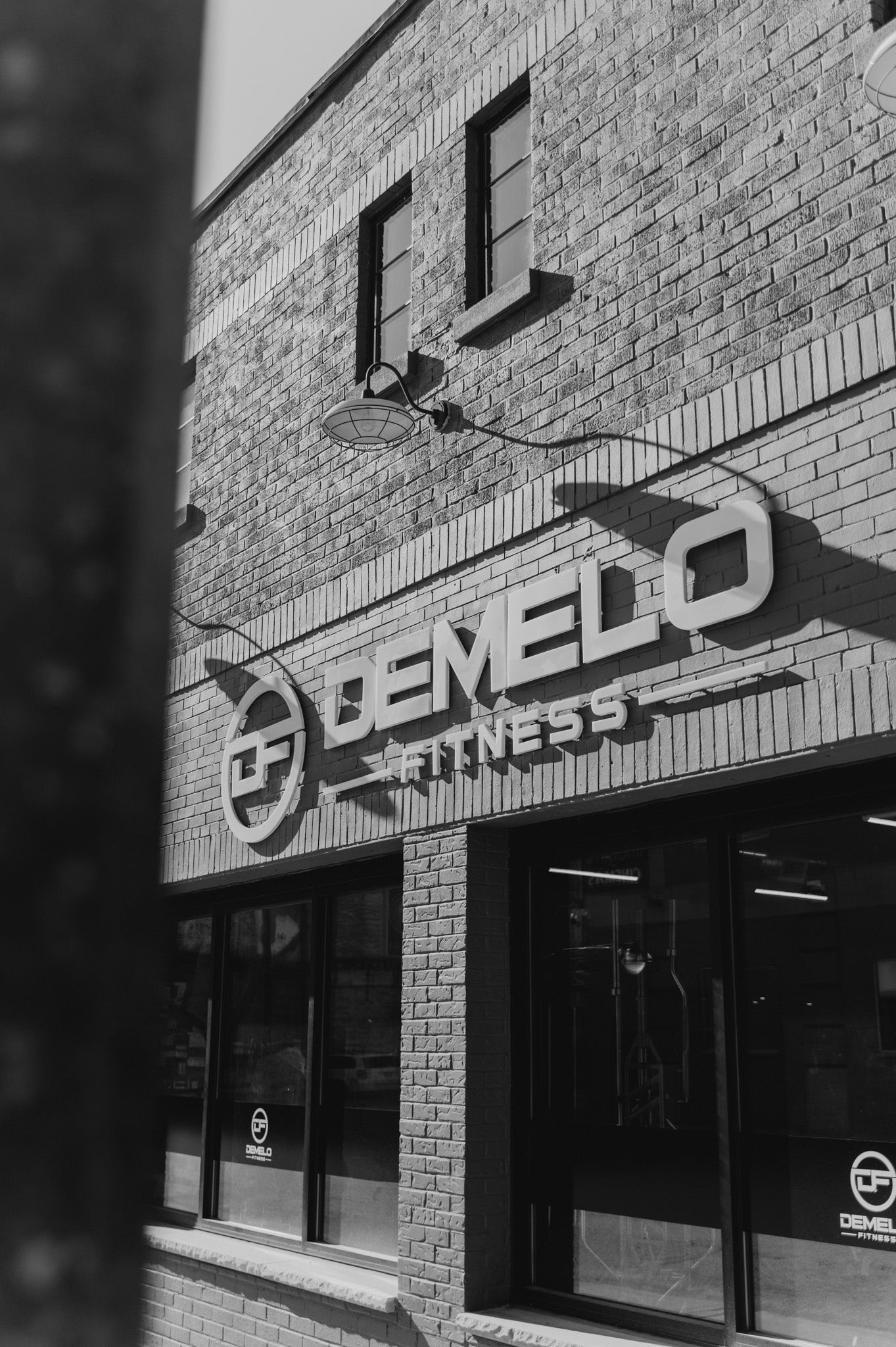 DeMelo Fitness building exterior in a grayscale, displaying the logo on the front of the building